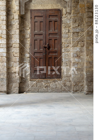 Facade of old abandoned stone bricks wall with grunge weathered wooden door Facade of old abandoned stone bricks wall with grunge weathered wooden door 88223130