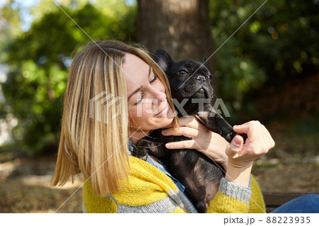 woman sitting on a bench with french bulldog woman sitting on a bench with french bulldog 88223935