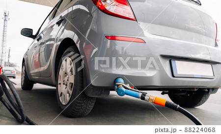 Person pumping gas. Fuel petrol for car at gasoline oil station nozzle in tank. Hand and black refueling gun close-up. Person pumping gas. Fuel petrol for car at gasoline oil station nozzle in tank. Hand and black refueling gun close-up. 88224068