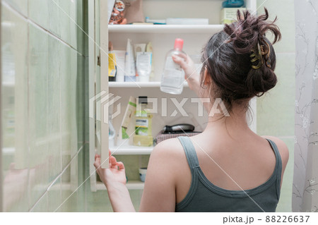 Beautiful girl choosing beauty products from the bathroom shelf and take it Beautiful girl choosing beauty products from the bathroom shelf and take it 88226637