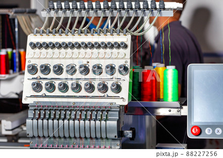 Programmable industrial embroidery machine with multi colored threads and tension system. Closeup, selective focus. Programmable industrial embroidery machine with multi colored threads and tension system. Closeup, selective focus. 88227256
