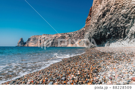 view of the sunset sea and the beach, the volcanic rock is lit by the warm sunset, sand and pebbles, volcanic basalt as in Iceland. Copy space. The concept of calmness, silence and unity with nature. view of the sunset sea and the beach, the volcanic rock is lit by the warm sunset, sand and pebbles, volcanic basalt as in Iceland. Copy space. The concept of calmness, silence and unity with nature. 88228509