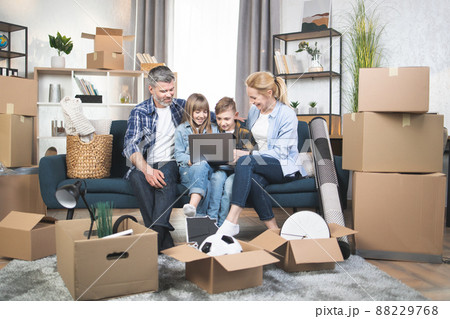 Caucasian parents with two teen kids using laptop at new flat Caucasian parents with two teen kids using laptop at new flat 88229768
