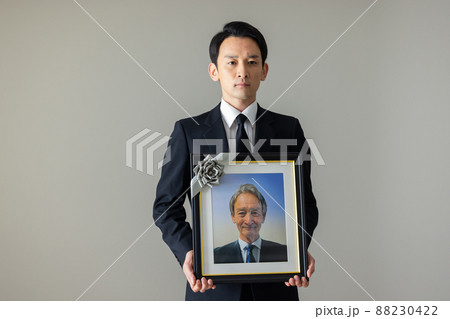 シニア男性の遺影を持つ若い男性 シニア男性の遺影を持つ若い男性 88230422