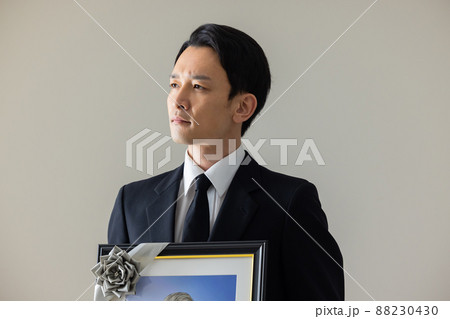 シニア男性の遺影を持つ若い男性 88230430