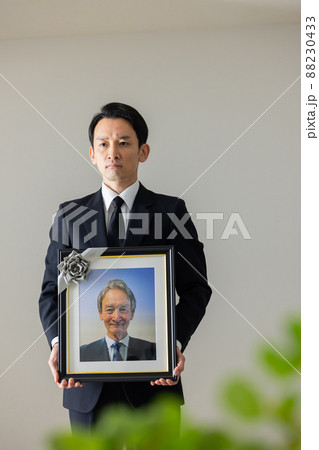 シニア男性の遺影を持つ若い男性 シニア男性の遺影を持つ若い男性 88230433