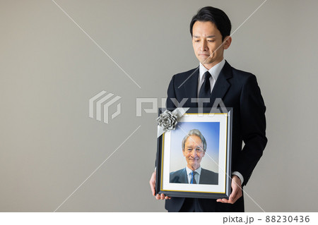 シニア男性の遺影を持つ若い男性 シニア男性の遺影を持つ若い男性 88230436