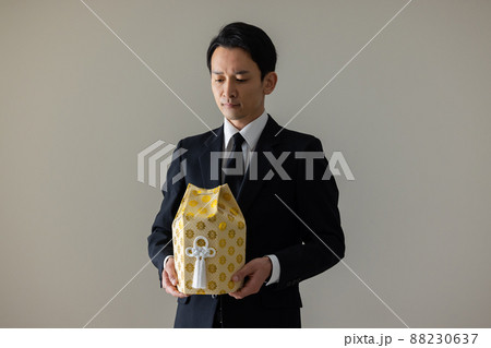 遺骨を抱く喪服の男性　 88230637