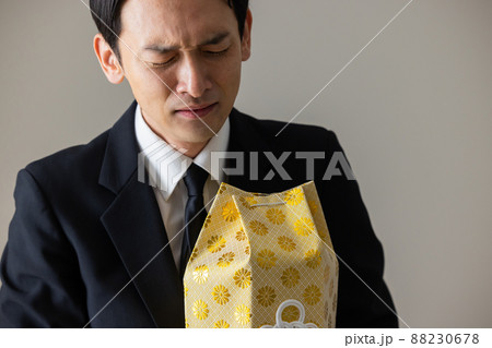 遺骨を抱いて泣く男性　　 88230678