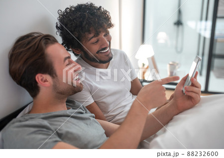 Male showing photos on the cellphone to his partner Male showing photos on the cellphone to his partner 88232600