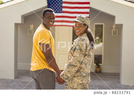 Portrait of happy female mid adult african american soldier holding hand of husband on arrival Portrait of happy female mid adult african american soldier holding hand of husband on arrival 88233791