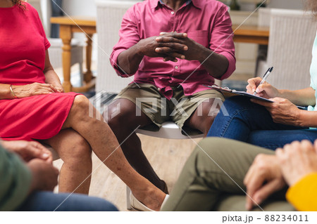 Midsection of multiracial senior men and women discussing during group therapy session 88234011
