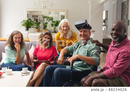 Smiling multiracial senior man and woman with handicap male friend wearing vr headset at home 88234026
