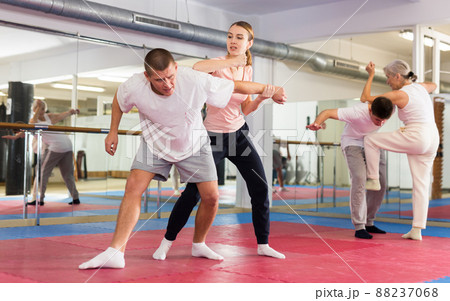 Young woman practicing elbow blow with wristlock to opponent in gym 88237068