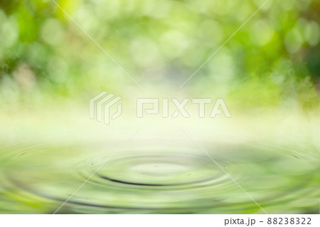 Drop falling in water with ripples with light green bokeh background. 88238322
