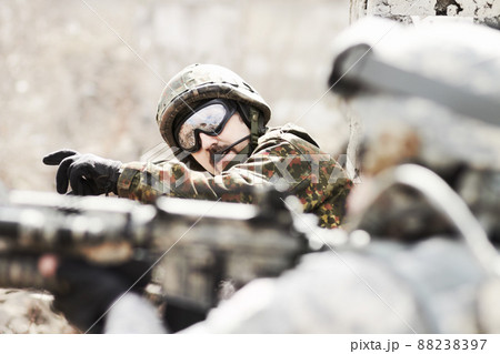Leading his platoon. Profile of a commandant giving orders to his soldiers while lying flat on the ground with guns in hand. 88238397