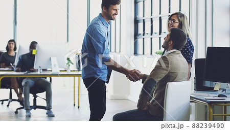 Lets get to work. Cropped shot of two businessmen shaking hands while working in their office. 88239490