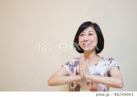 合掌して呼吸法をする笑顔の中年女性 合掌して呼吸法をする笑顔の中年女性 88240063