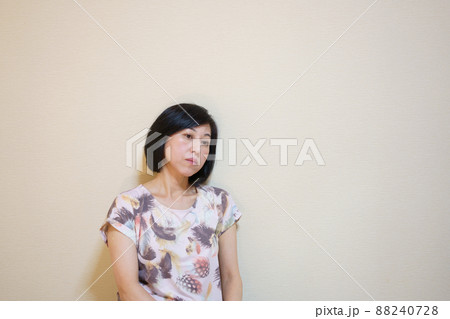 下を向いて壁に寄りかかり落ち込む中年女性 88240728