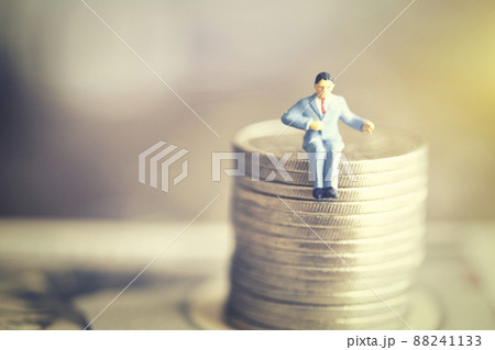 お金に座るミニチュアのビジネスマン お金に座るミニチュアのビジネスマン 88241133