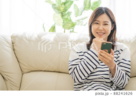 スマホで通販サイトを見て買い物をする30代女性 スマホで通販サイトを見て買い物をする30代女性 88241626