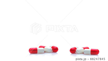Group of red-white capsule pills on horizontal white background. Prescription drugs. Pharmacy drugstore web banner. Healthcare and medical background. Drug production. Daily dose for love booster. 88247845