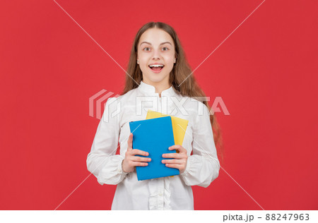 amazed child in white shirt ready to study do homework with book on red background, back to school amazed child in white shirt ready to study do homework with book on red background, back to school 88247963