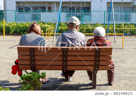 公園のベンチに座って話をする仲良しシニア3人組 88248625