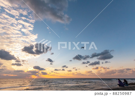 沖縄　北谷　宮城海岸で夕日を見る女性 88250987