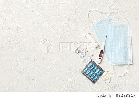 Protective face masks or surgical masks, medicine pills and thermometer on table background. Coronavirus disease. Corona virus concept. Space for text Protective face masks or surgical masks, medicine pills and thermometer on table background. Coronavirus disease. Corona virus concept. Space for text 88253817