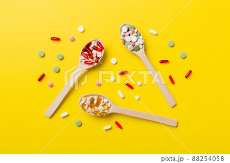 Vitamin capsules in a wooden spoon on a colored background. Pills served as a healthy meal. Drugs, pharmacy, medicine or medical healthycare concept Vitamin capsules in a wooden spoon on a colored background. Pills served as a healthy meal. Drugs, pharmacy, medicine or medical healthycare concept 88254058