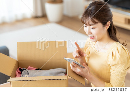 リビングで段ボールに荷造りする女性 88255857