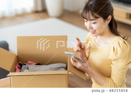 リビングで段ボールに荷造りする女性 88255858