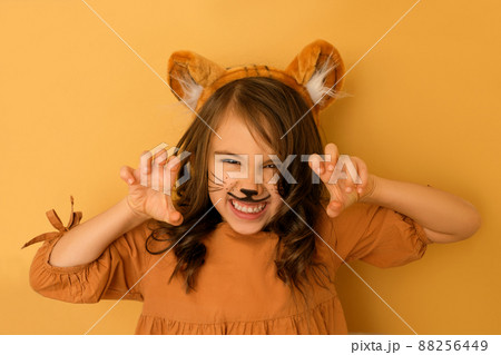 A curly-haired brunette girl with a tiger's rim and ears and a painted face growls, showing her teeth and making a gesture with her hands. The Year of the Tiger according to the Eastern calendar A curly-haired brunette girl with a tiger's rim and ears and a painted face growls, showing her teeth and making a gesture with her hands. The Year of the Tiger according to the Eastern calendar 88256449