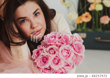 Closeup portrait of a beautiful happy bride in jacket on the floor holding a rose bouquet. Closeup portrait of a beautiful happy bride in jacket on the floor holding a rose bouquet. 88257472