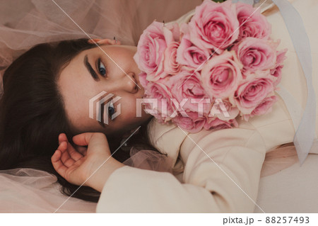 Closeup portrait of a beautiful happy bride in jacket on the floor holding a rose bouquet Closeup portrait of a beautiful happy bride in jacket on the floor holding a rose bouquet 88257493