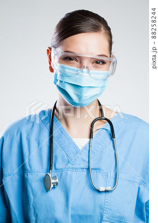 Happy satisfied female doctor wearing protective face mask & safety goggles 88258244