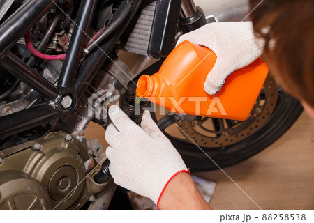 The process of pouring new oil into the motorcycle engine. The process of pouring new oil into the motorcycle engine. 88258538