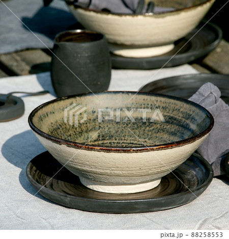 Rustic table setting outside in garden with empty craft ceramic tableware Rustic table setting outside in garden with empty craft ceramic tableware 88258553