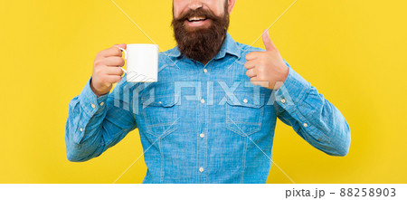 Happy man crop view giving thumbs up holding coffee mug yellow background, copy space Happy man crop view giving thumbs up holding coffee mug yellow background, copy space 88258903