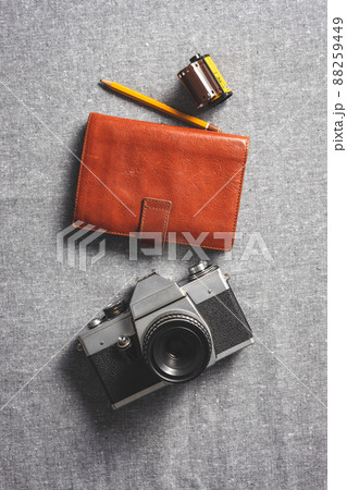 Retro analogue camera. Vintage old fashioned camera with lens with notebook and roll of photographic film 88259449