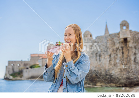 Young woman tourist eating traditional pizza in the old town of Budva. Travel to Montenegro concept 88262639