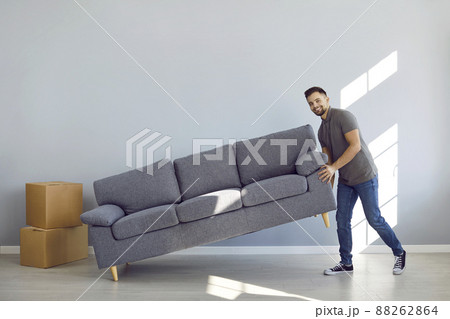 Happy man lifting sofa while furnishing the living room in his new house or apartment 88262864