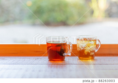 【日本】東京、窓際のカウンターテーブル上に置かれたホットティーとアイスティーの入ったガラスカップ 88263003