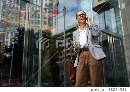Communication. Portrait of happy fashionable business woman wearing eyeglasses and classic wear talking on mobile phone 88264581