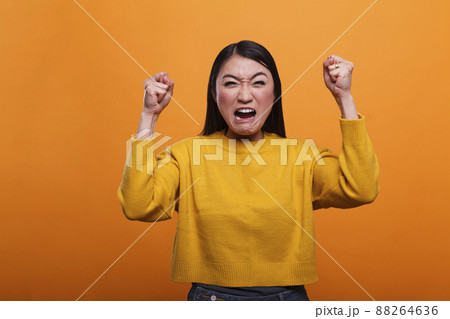 Mad furious asian woman angered and annoyed by loud music heard from neighbors. Upset frustrated person aggressively yelling while having a quarrel with friend about rage conflict and stress. 88264636