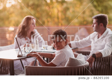 An elderly couple enjoys the terrace of a luxury house with their son during the holidays. Selective focus  88265100