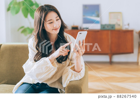 ソファに座ってスマホを見る女性 ソファに座ってスマホを見る女性 88267540
