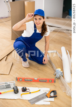 Woman builder puts laminate on the floor in room Woman builder puts laminate on the floor in room 88268425