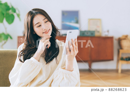 ソファに座ってスマホを見る女性 88268623